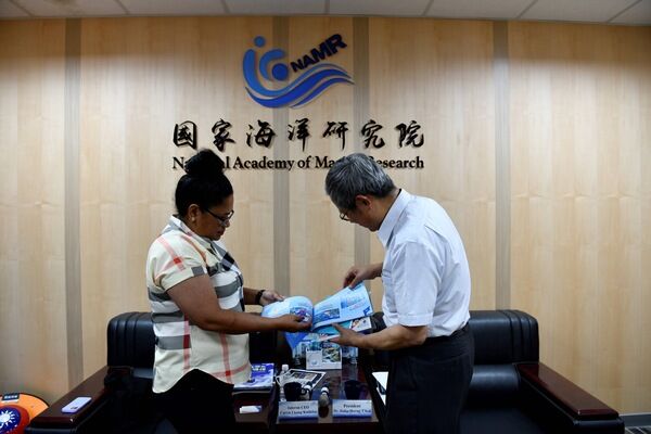 國海院院長陳建宏向帛琉國際珊瑚礁中心代理執行長Caryn Lkong Koshiba介紹全國兒童海洋繪畫比賽作品集